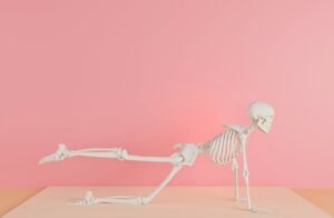 Advice & Resources A human skeleton model posing in a yoga stance against a pink backdrop.