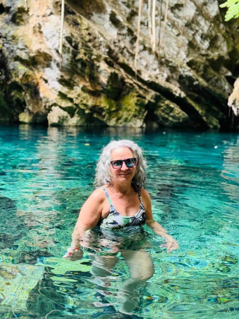 Exercising With Osteoarthritis: Is Some Pain Okay? Elegant senior woman swims in clear turquoise water of a rocky natural pool.